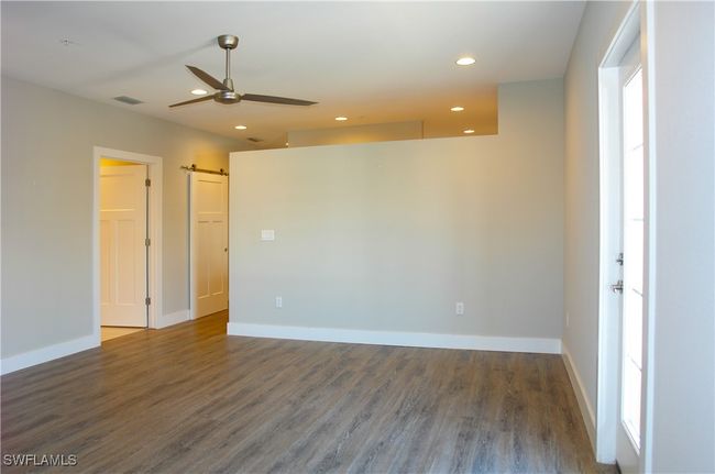 Empty room featuring ceiling fan, wood finished floors, a barn door, and recessed lighting | Image 11