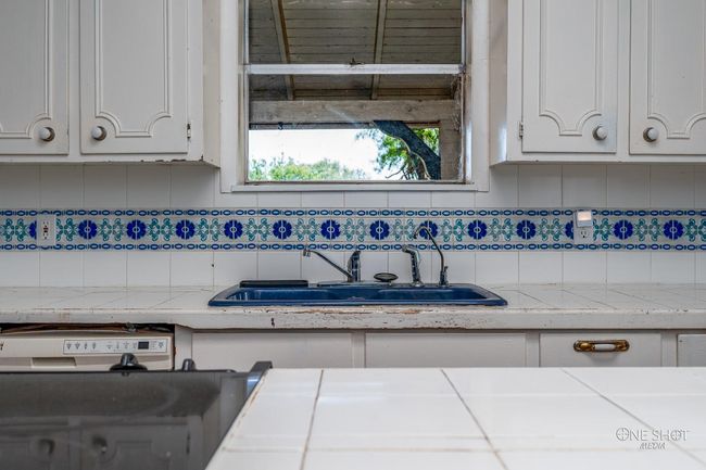 Kitchen featuring backsplash, white cabinetry, and sink | Image 12