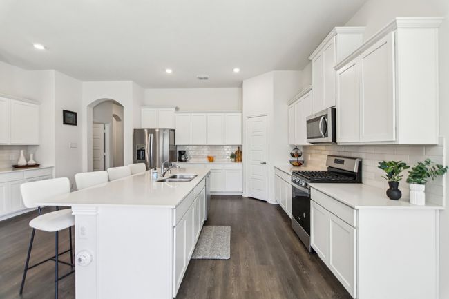 Kitchen with dark wood-type flooring, arched walkways, a breakfast bar, a sink, and stainless steel appliances | Image 11