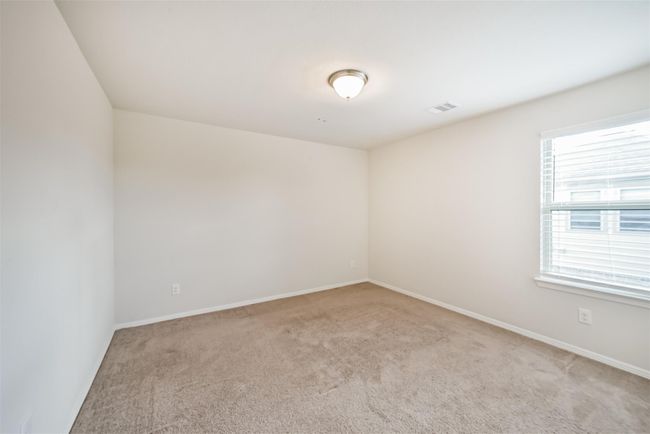 This upstairs bedroom 3 is a bright, neutral-toned space with a cozy carpeted floor, a ceiling light, and a window allowing natural light. Perfect for a bedroom or office. | Image 26
