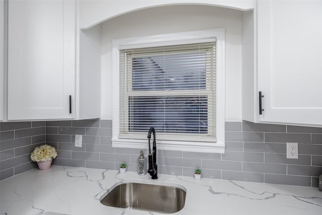 Details featuring white cabinets, light stone countertops, and sink | Image 19