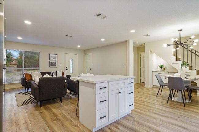 Kitchen featuring a chandelier, light wood-type flooring, a center island, white cabinetry, and visible vents | Image 10