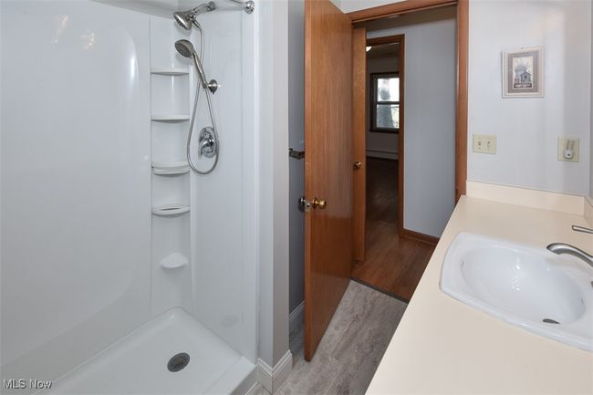 Bathroom featuring baseboards, vanity, wood finished floors, and a shower | Image 39