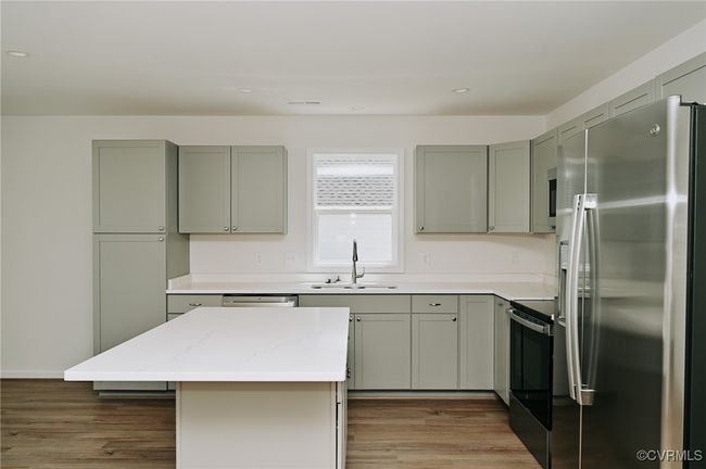 Kitchen featuring a kitchen island, sink, light stone countertops, dark wood-type flooring, and stainless steel appliances | Image 15