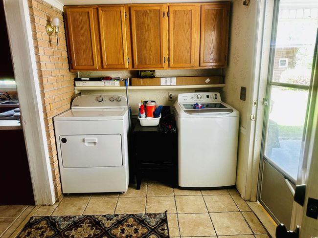 Laundry area with independent washer and dryer, a healthy amount of sunlight, light tile patterned flooring, and cabinet space | Image 9