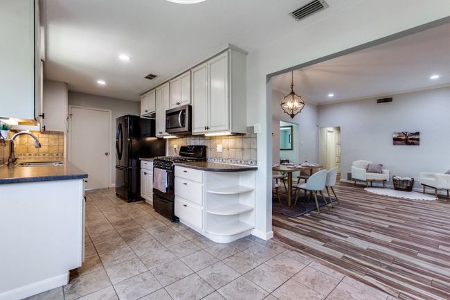 Kitchen with black appliances, dark countertops, open shelves, tasteful backsplash, and recessed lighting | Image 6
