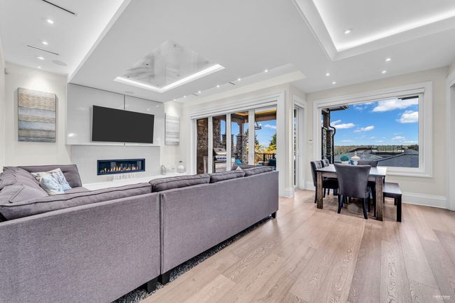 Living room with recessed lighting, a raised ceiling, light wood-style flooring, and a glass covered fireplace | Image 23