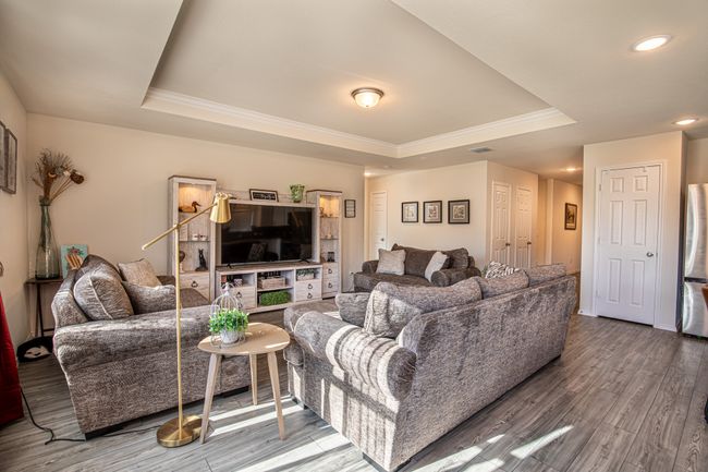 Living area with a raised ceiling, ornamental molding, wood finished floors, and recessed lighting | Image 12