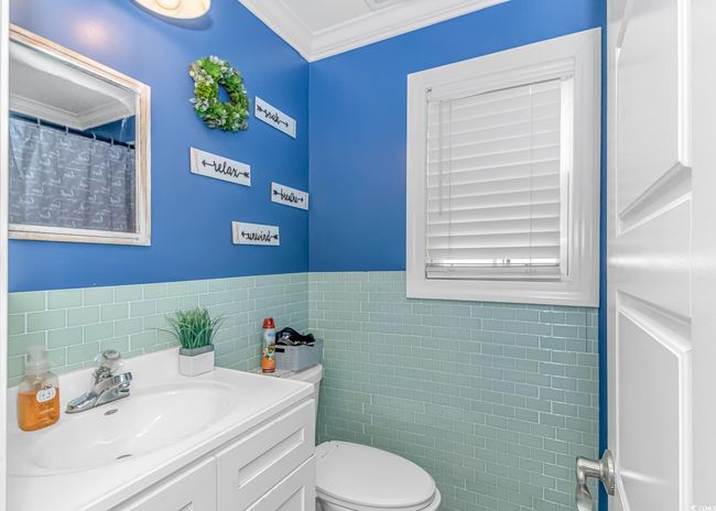 Bathroom with tile walls, ornamental molding, toilet, vanity, and wainscoting | Image 13