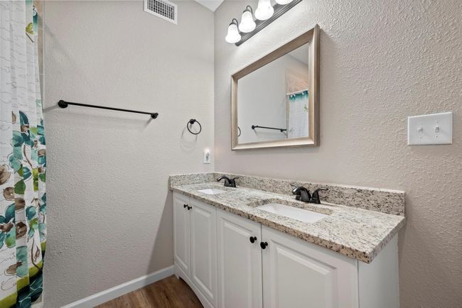 Primary en suite bath featuring double vanity, wood finished floors, visible vents, and a sink | Image 7