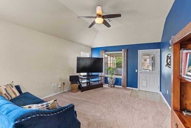 Living room with vaulted ceiling, ceiling fan, carpet floors, baseboards, and tile patterned flooring | Image 4