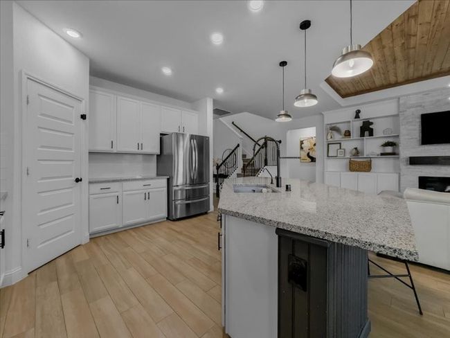 Kitchen with freestanding refrigerator, open floor plan, light wood-type flooring, white cabinetry, and recessed lighting | Image 7