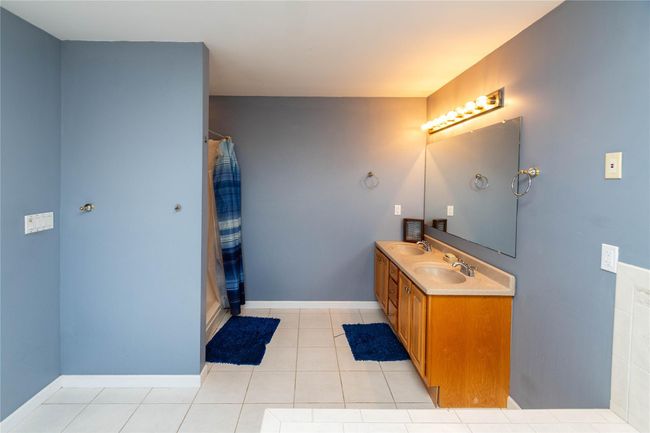 Full bathroom with tile patterned floors, baseboards, a shower with curtain, and a sink | Image 31
