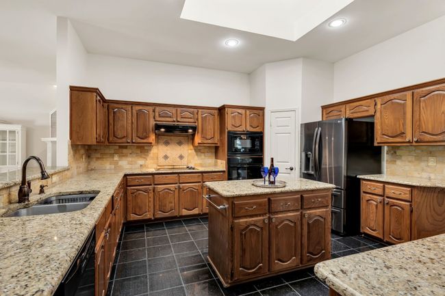 Kitchen with granite countertop, backsplash, under cabinet range hood | Image 11