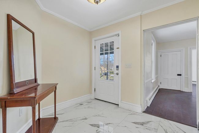 Entryway with baseboard heating, baseboards, ornamental molding, and marble look tile flooring | Image 4