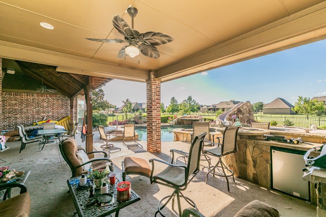 Fenced backyard with a patio area, an outdoor bar, and ceiling fan | Image 33