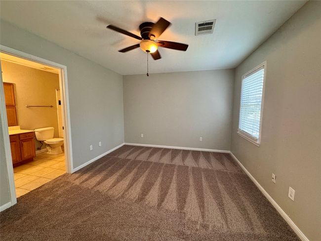 Unfurnished bedroom with light colored carpet, ensuite bath, and ceiling fan | Image 15
