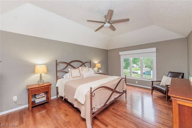 Bedroom with vaulted ceiling, ceiling fan, hardwood / wood-style flooring, and a textured ceiling | Image 25