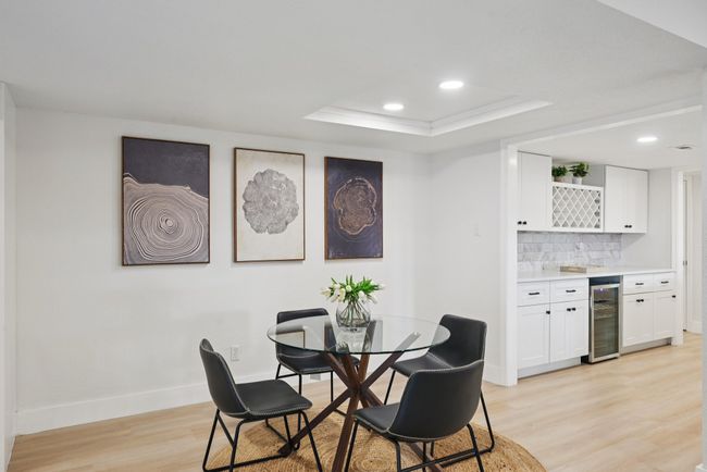 Dining space with wine cooler, bar with sink, light wood-style floors, a tray ceiling, and recessed lighting | Image 17