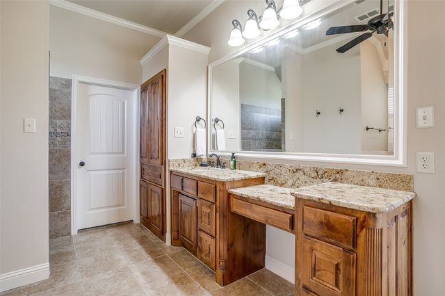 Full bathroom with vanity, ornamental molding, tiled shower, visible vents, and ceiling fan | Image 16