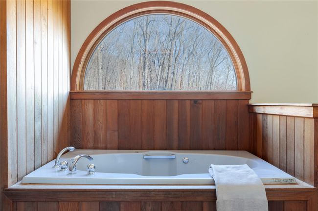 Bathroom featuring a jetted tub and wooden walls | Image 7