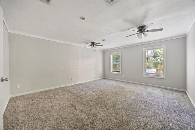 Carpeted empty room featuring a ceiling fan, a textured ceiling, and ornamental molding | Image 15