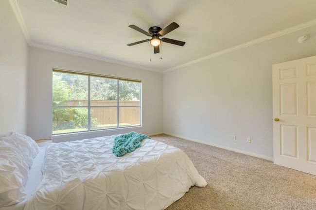 Bedroom with light colored carpet, crown molding, and ceiling fan | Image 18