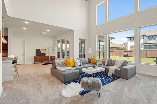 Living room featuring baseboards, a towering ceiling, carpet floors, and a healthy amount of sunlight | Image 6
