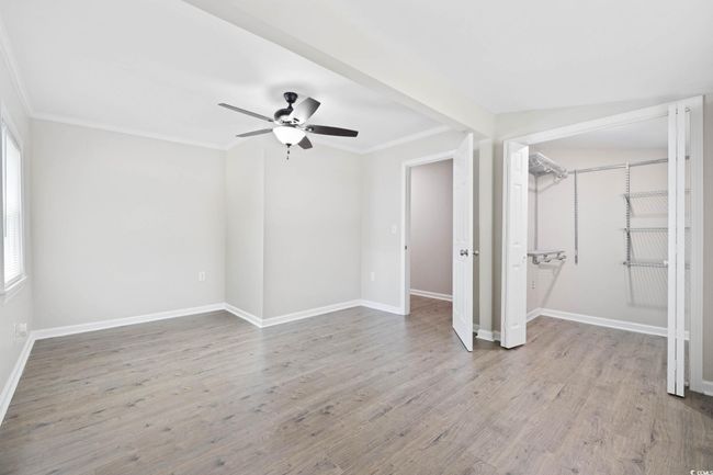 Unfurnished bedroom with crown molding, wood finished floors, baseboards, and ceiling fan | Image 14