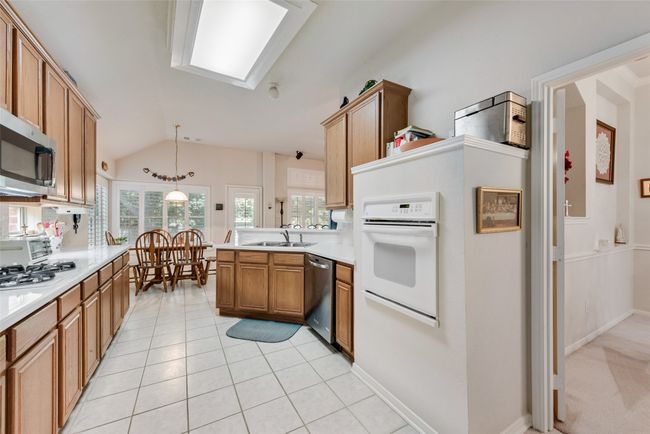 Kitchen with stainless steel appliances, a sink, lofted ceiling, light countertops, and a peninsula | Image 14
