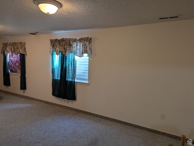 Carpeted empty room featuring a textured ceiling, visible vents, and baseboards | Image 10