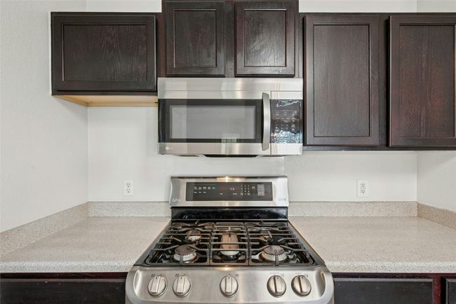 Kitchen featuring stainless steel appliances, dark brown cabinets, and light countertops | Image 10