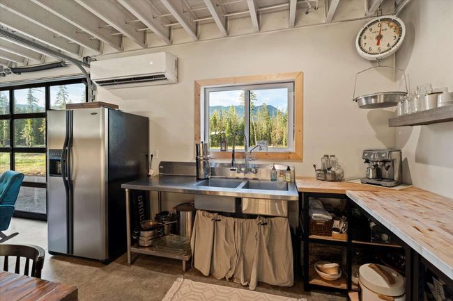 Kitchen with stainless steel refrigerator with ice dispenser, a wall mounted AC, butcher block countertops, and plenty of natural light | Image 21