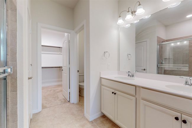 Bathroom featuring a stall shower, double vanity, a walk in closet, tile patterned floors, and toilet | Image 21