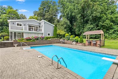 View of swimming pool featuring a diving board and a patio area | Image 2