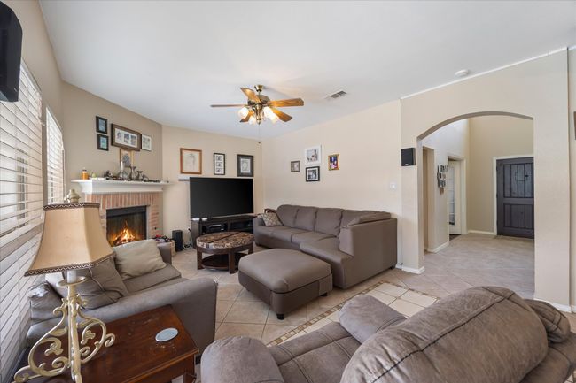 Living room featuring arched walkways, light tile patterned floors, ceiling fan, and a fireplace | Image 16