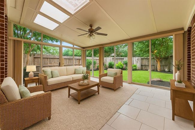 Surrounded by walls of glass, this light-filled sunroom offers beautiful backyard views and year-round enjoyment. With tile flooring, skylights, 2 sliding doors, a doggie door. and a ceiling fan, it's the perfect spot to relax, entertain, or create a flexible second living space. This fully enclosed space is both air conditioned and heated for year-round comfort. virtually staged | Image 33
