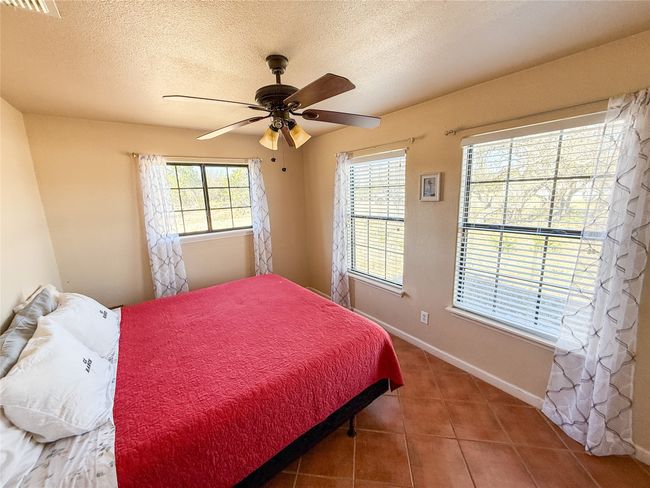 Bedroom with baseboards, a textured ceiling, tile patterned floors, and a ceiling fan | Image 14