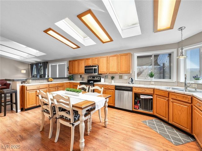 Kitchen with light wood finished floors, light countertops, a peninsula, stainless steel appliances, and a sink | Image 21