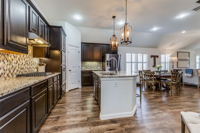 Kitchen with gas cooktop. Continuous wood flooring throughout main living area. | Image 12