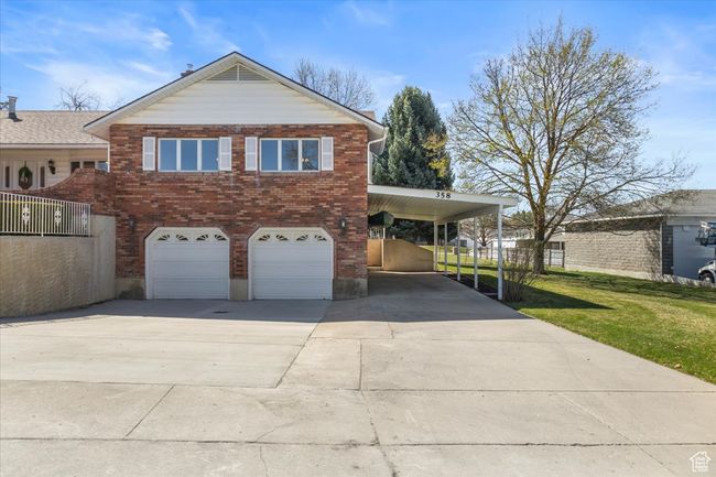 View of front of property featuring a carport, a front yard, brick siding, an attached garage, and driveway | Image 44