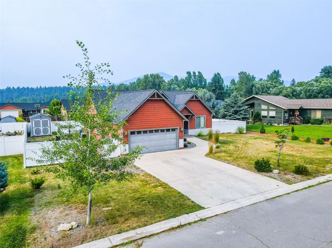 View of front facade featuring a mountain view, concrete driveway, a front yard, and fence | Image 15