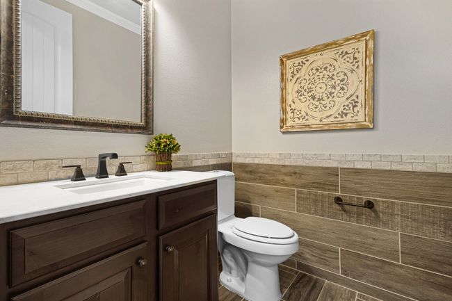 Half bath with toilet, vanity, tile walls, ornamental molding, and a wainscoted wall | Image 22