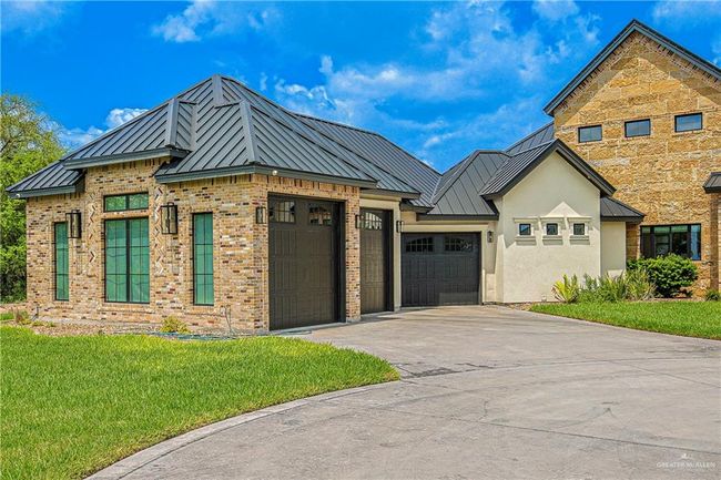 View of front of home with a standing seam roof, an attached garage, a front yard, concrete driveway, and a metal roof | Image 4