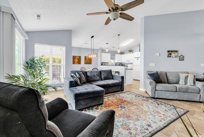 Living area with vaulted ceiling, a ceiling fan, and light tile patterned floors | Image 16