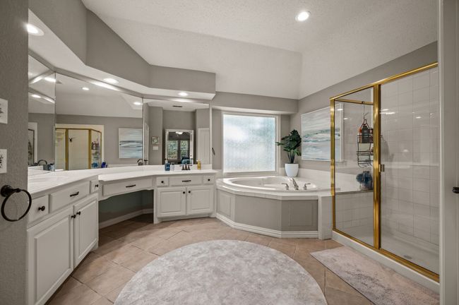 Full bath featuring a shower stall, a garden tub, vanity, lofted ceiling, and light tile patterned floors | Image 22