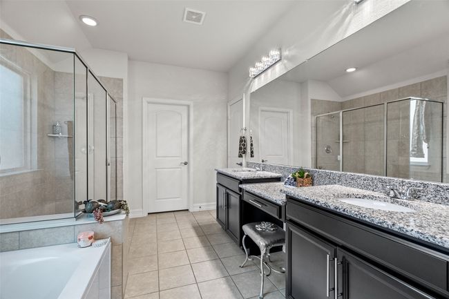 Bathroom featuring two vanities, tile patterned flooring, a shower stall, visible vents, and a sink | Image 17