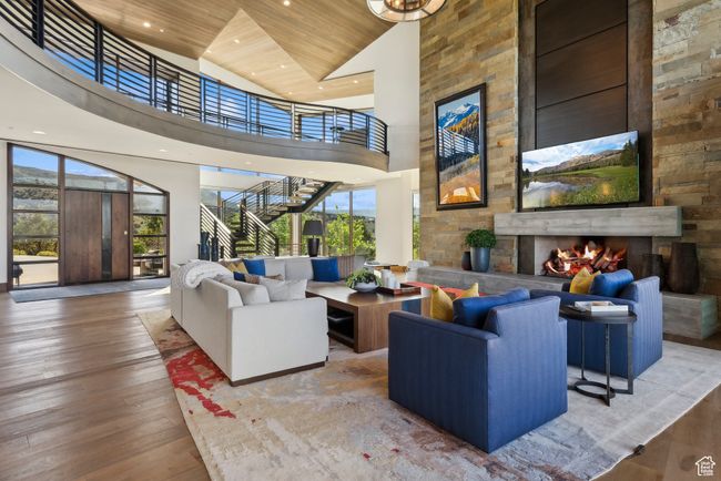 Living room featuring a towering ceiling, an outdoor stone fireplace, wooden ceiling, wood-type flooring, and recessed lighting | Image 24