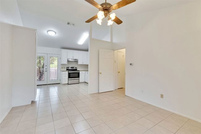 Unfurnished living room featuring ceiling fan, light tile patterned floors, and a towering ceiling | Image 15