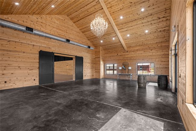 Front foyer featuring high vaulted ceiling, wooden walls, wooden ceiling, a chandelier, and concrete flooring | Image 8